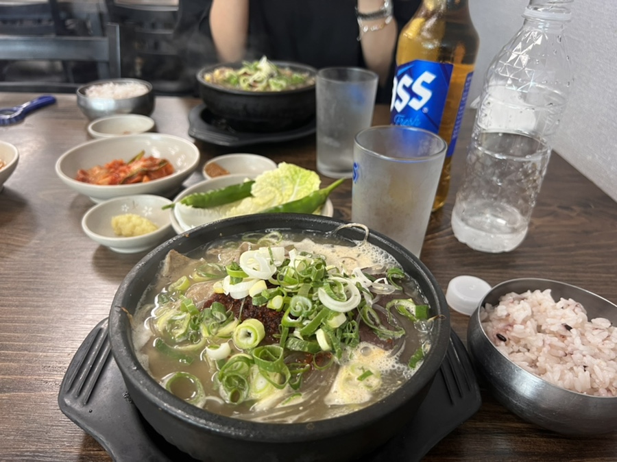 은희네해장국의 대표 메뉴인 해장국과 함께 주문한 시원한 맥주가 한상에 차려진 모습으로 제주 여행 중 해장 식사로 즐기기 좋다.