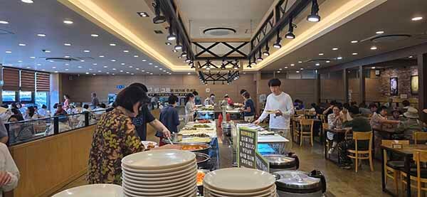 뷔페 코너 앞에서 음식 고르는 손님들