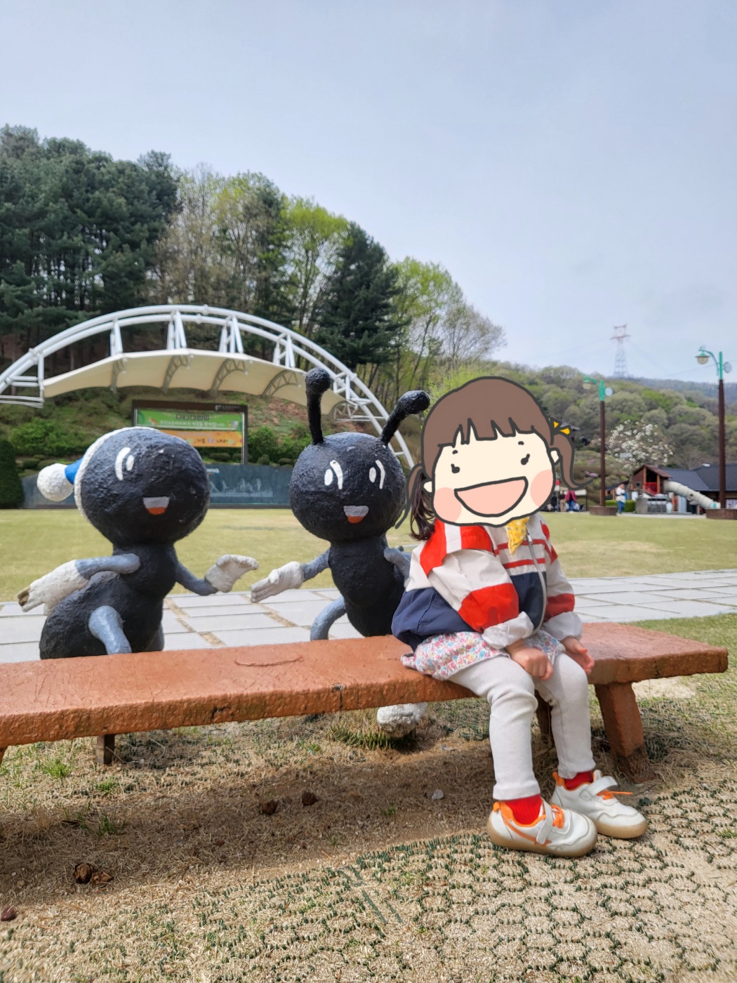 개미 조형물 앞에 앉은 아이