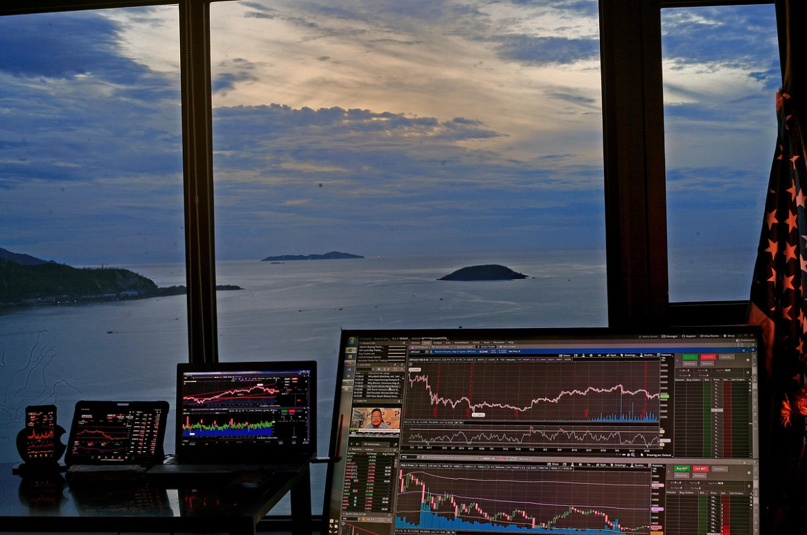 주식창이 띄워진 모니터 뒤에 바다가 보이는 창