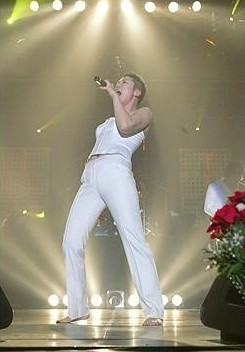 이은미가-흰색-민소매-셔츠와-흰색-바지를-입고-맨발로-열창하는-사진