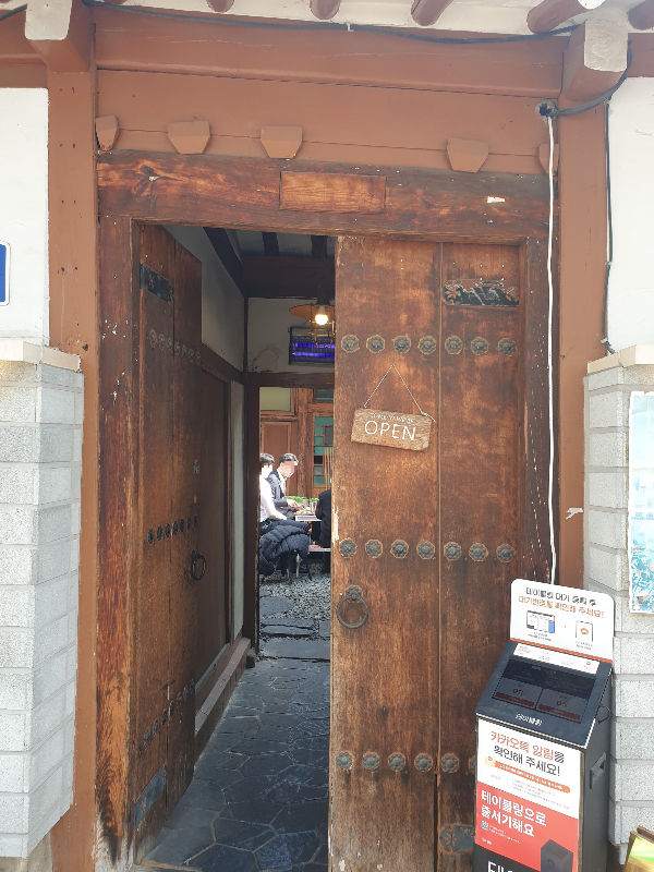 대문 안으로 야외에서 식사를 즐기는 사람들이 보인다.