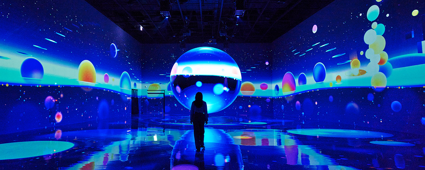 르 스페이스 전시관의 외계 행성 테마 공간. 거대한 구형 오브젝트와 다채로운 빛의 행성들이 360도 몰입형 영상으로 구현되어 있다.