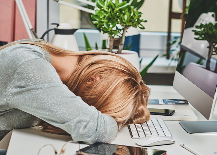 업무에 지친 여성이 책상에 엎드려 있다