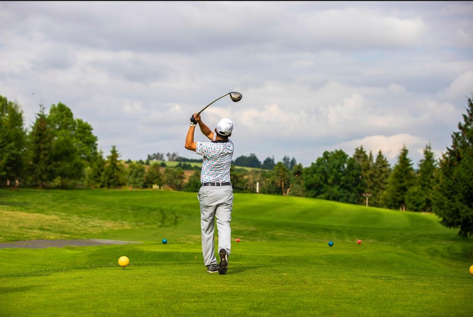 넓은 골프장에서 공을 치고 있는 남자의 뒷모습을 찍은 사진