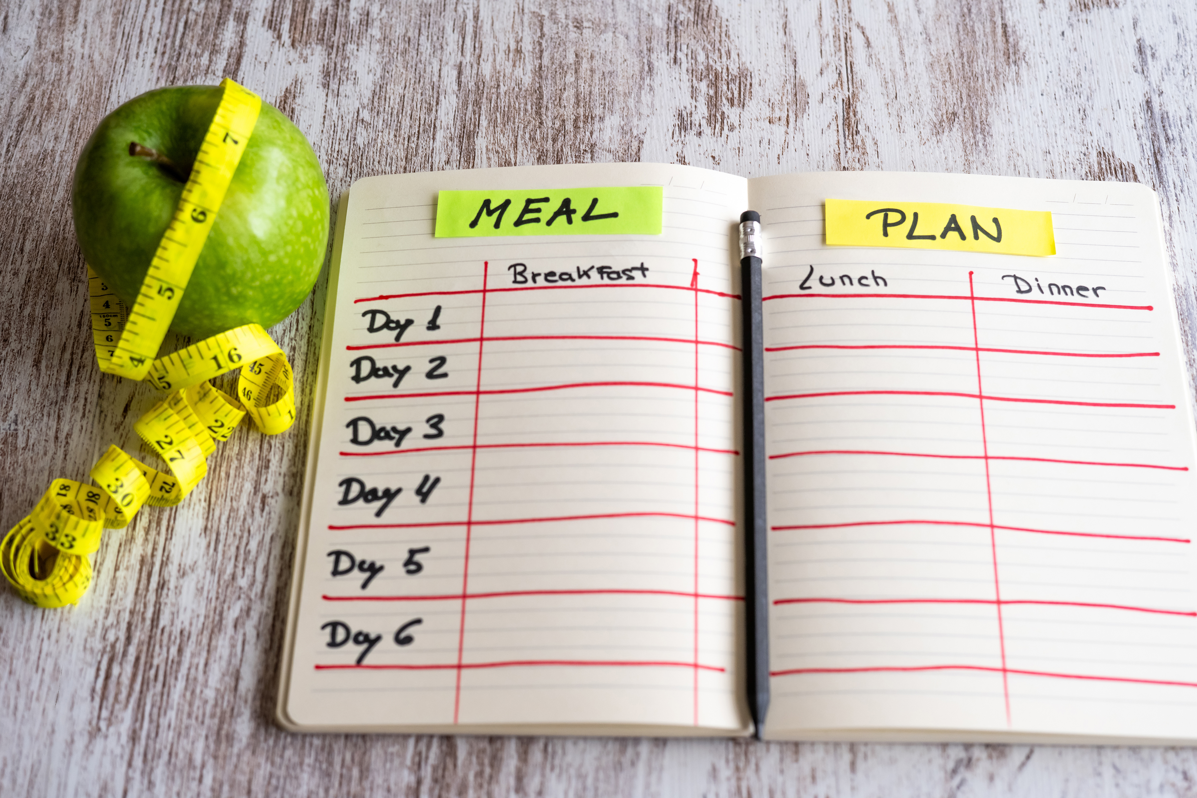 다이어트 식단 계획표와 줄자, 초록 사과가 함께 놓인 테이블 &ndash; 체계적인 식사 기록과 심리적 동기부여를 상징하는 이미지