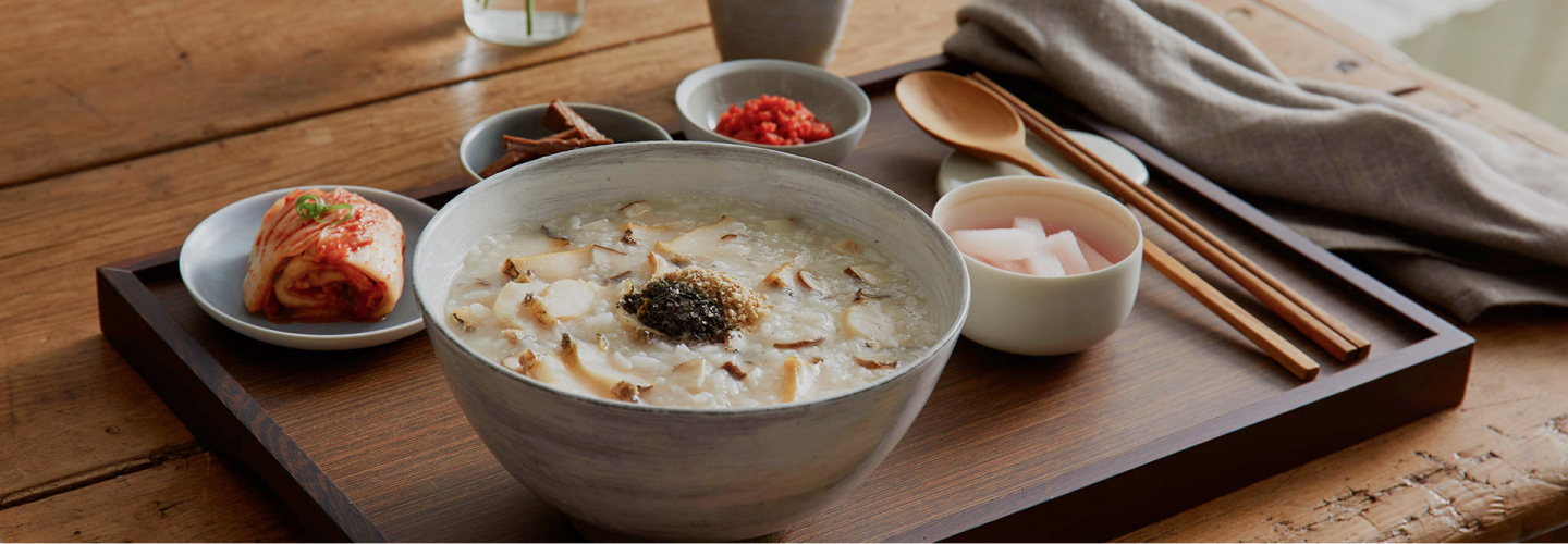 죽과 김치&amp;#44; 돼지고기 장조림이 정갈한 그릇에 담겨서 나무 쟁반위에 올려진 이미지