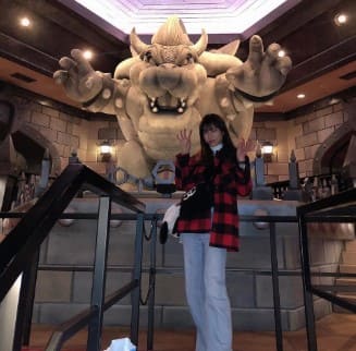 실물 크기의 캐릭터 동상앞에 여자가 서서 같은 포즈를 취하고 있다.