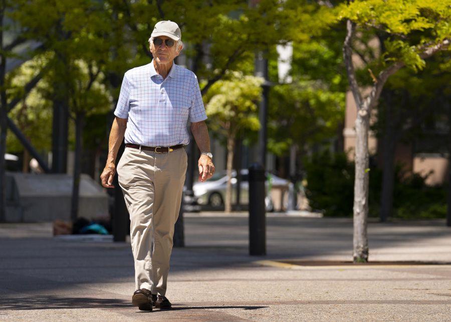 모자를 쓴 나이가 지긋한 서양 남성이 가벼운 옷차림을 하고 길에서 걷는 운동을 하고 있는 것을 찍은 사진