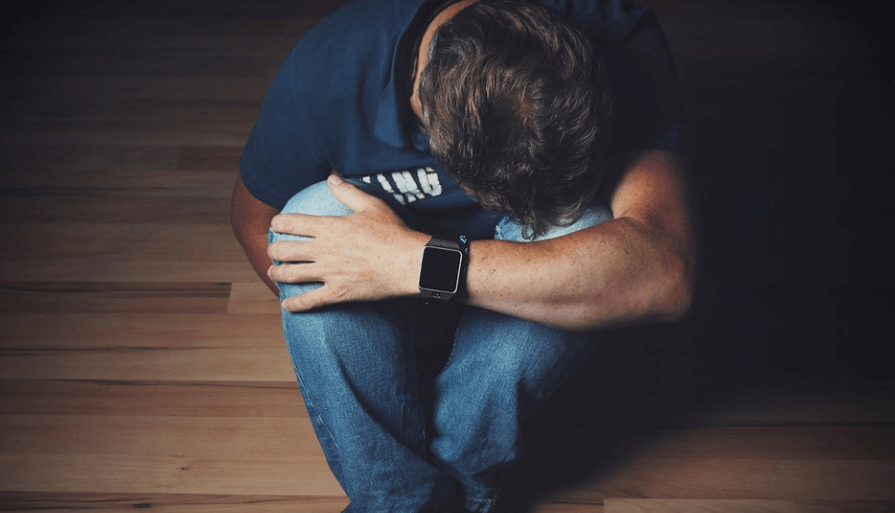 카페인 과다 섭취 증상으로 쪼그려 앉아서 불안감을 느끼고 있는 남성