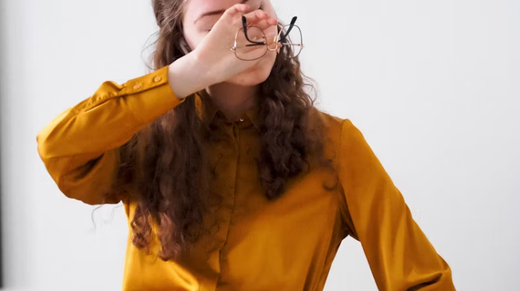 눈을 감고 피로를 느끼는 여성이 안경을 벗으며 눈을 쉬게 하는 모습