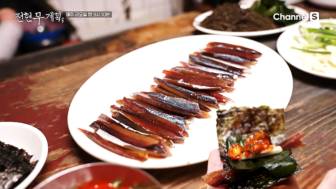 윤기 좌르르 흐르는 과메기를 각종 야채, 비법 초장과 함께 김에 싸는 모습