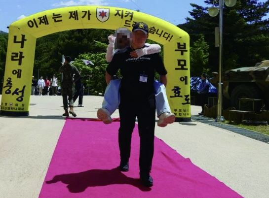 강원도 인제 12사단 군부대에서 훈련병이 '얼차려'를 받다 쓰러져 숨진 가운데 해당 훈련병의 어머니가 아들을 향한 그리움과 동시에 군을 비판했다. 사진은 숨진 훈련병이 입소식 당시 어머니를 업고 있는 모습. [사진=군인권센터]