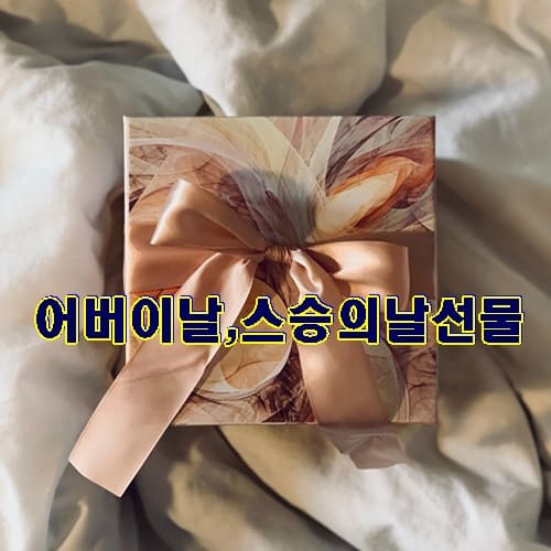 하얀천 위에 리본이 달린 선물 상자가 놓여있다 가운데 어버이날,스승의날 선물이라는 문구가 적혀있는 이미지