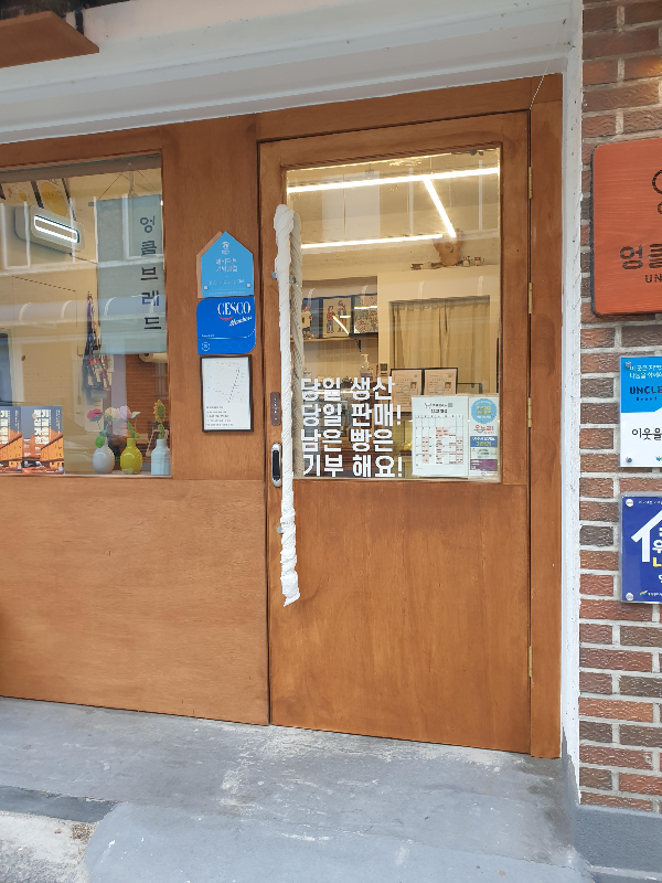 카페 출입문 당일 생산, 당일 판매, 남은 빵은 기부한다는 글귀가 보인다.