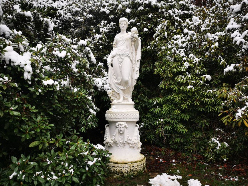 Elegant statue surrounded by snowy foliage in a tranquil Espenau garden.
