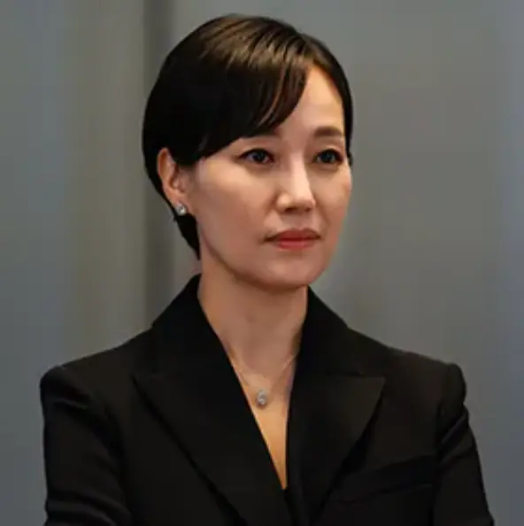 회색배경 실내에서 검은정장을 입고 살짝 미소지은 민혜숙