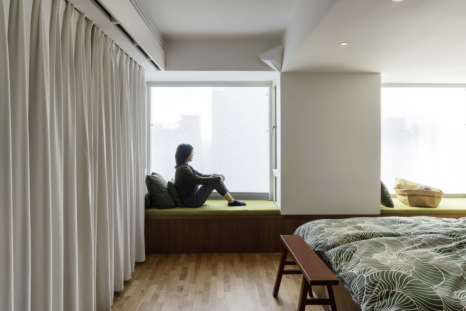 침실-내-한-여성이-무릎을-감싸고-앉아있다