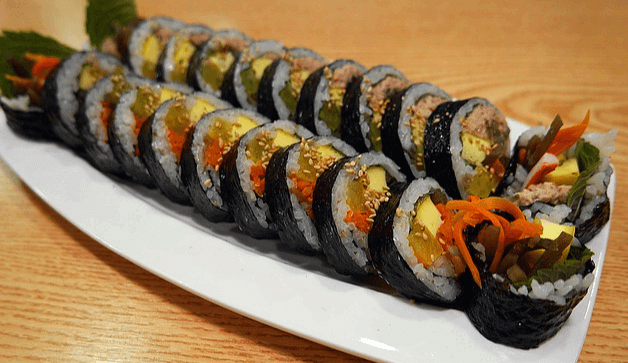 하얀 접시에 김밥 2줄이 썰어져서 놓여있다. 야채김밥과 참치김밥이다.