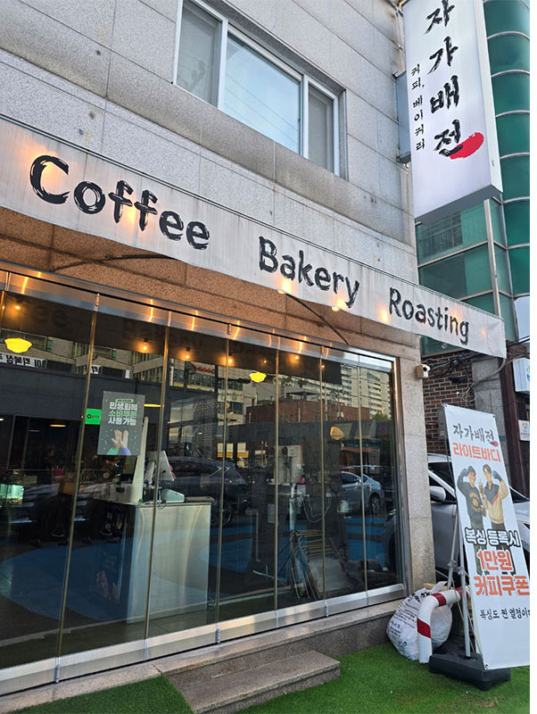 “유리창과 간판이 인상적인 동네 로스터리 카페 전경, 로스팅과 베이커리가 함께 보이는 모습.”