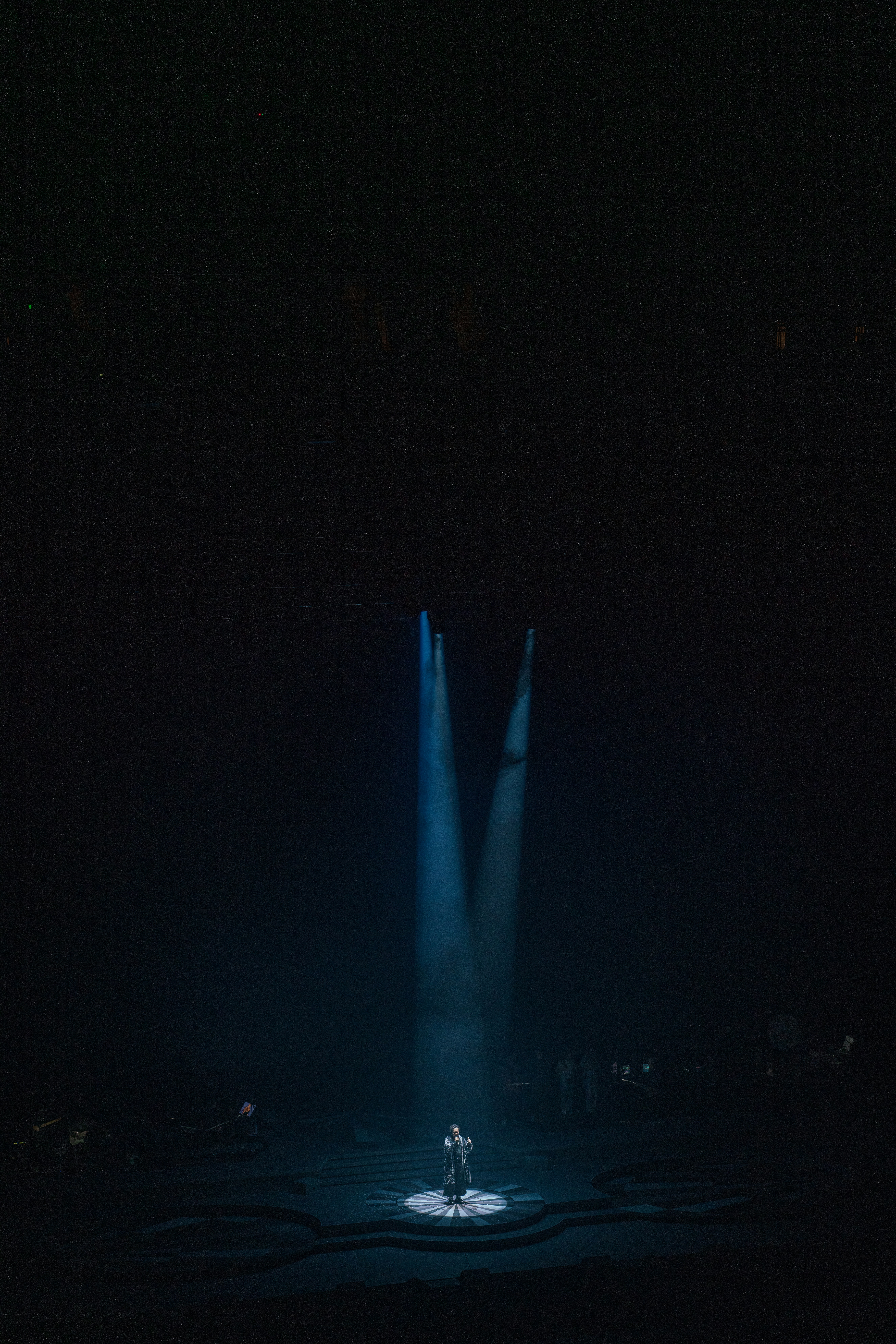 어두운 무대 조명 아래 홀로 서 있는 장면 관련 사진