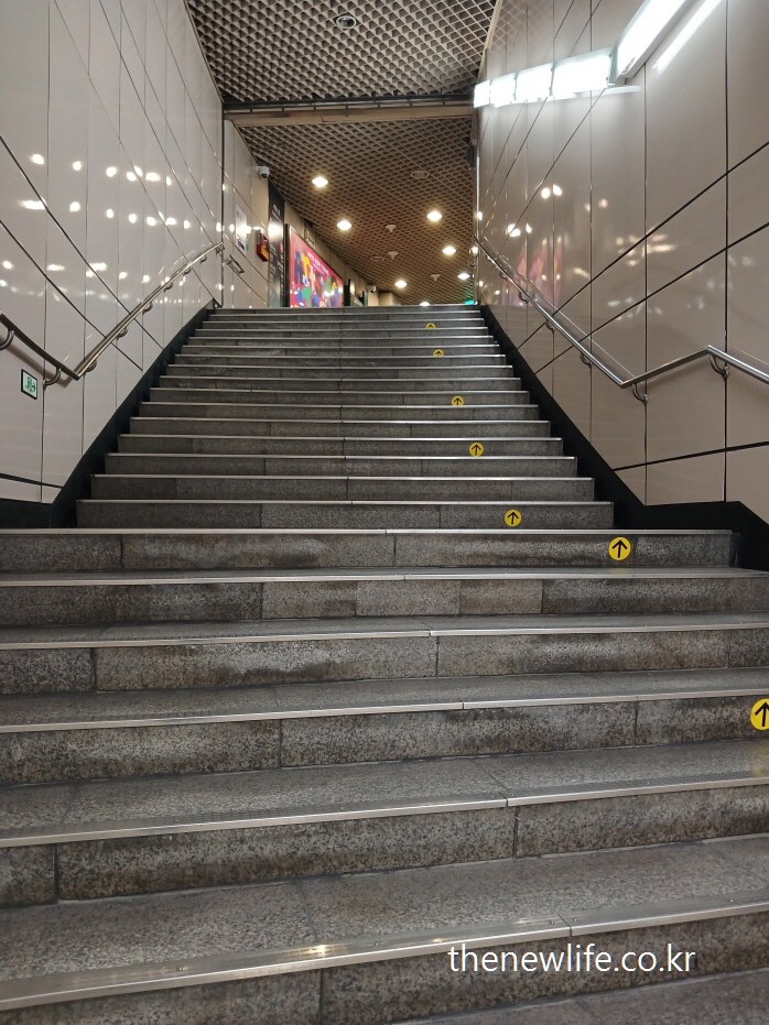 &ldquo;Indoor subway stairs with arrow markers for direction&rdquo;-&ldquo;지하철 내부 방향 표시가 있는 실내 계단&rdquo;