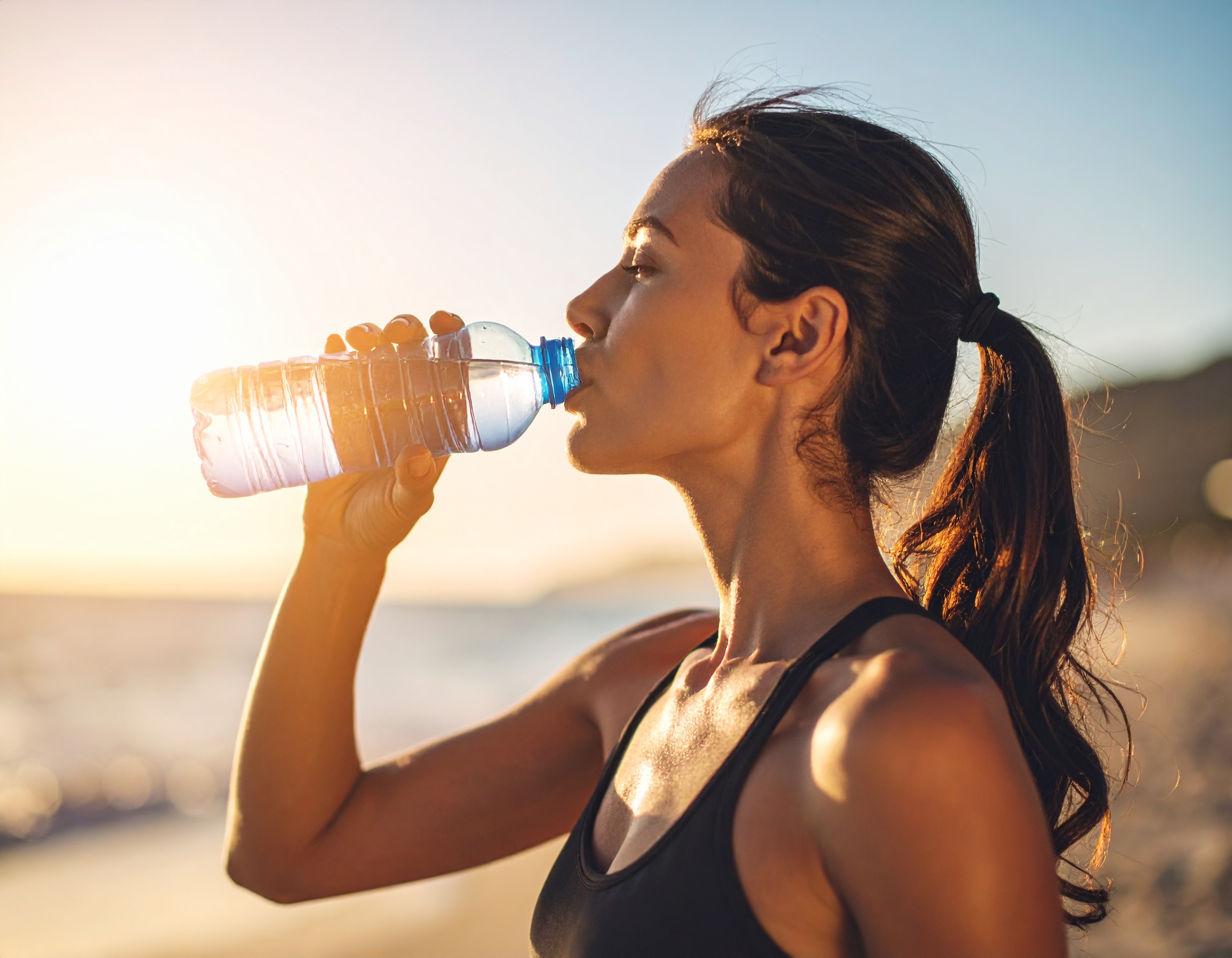 운동 후 해변에서 물을 마시는 여성