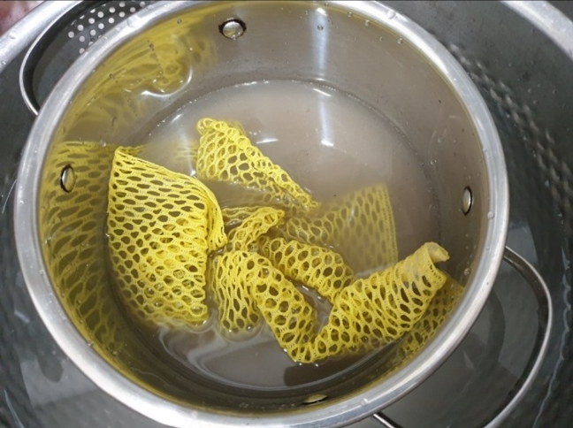 노란색의 그물 수세미로 냄비를 닦아낸 모습