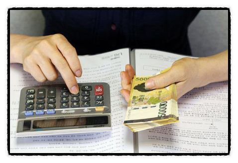 계산기와 지폐를 이용해 금전 계산 중인 손