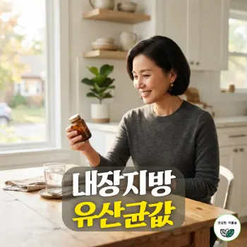 내장지방 유산균값. 50대 초반의 세련되고 단정한 한국인 중년 여성이 햇살이 부드럽게 비치는 밝은 원목 주방 식탁에 앉아, 유리잔의 따뜻한 물과 함께 고급스러운 건강기능식품 유산균 캡슐 병을 진지하게 살펴보며 미소를 짓고 있는 일상적인 모습.