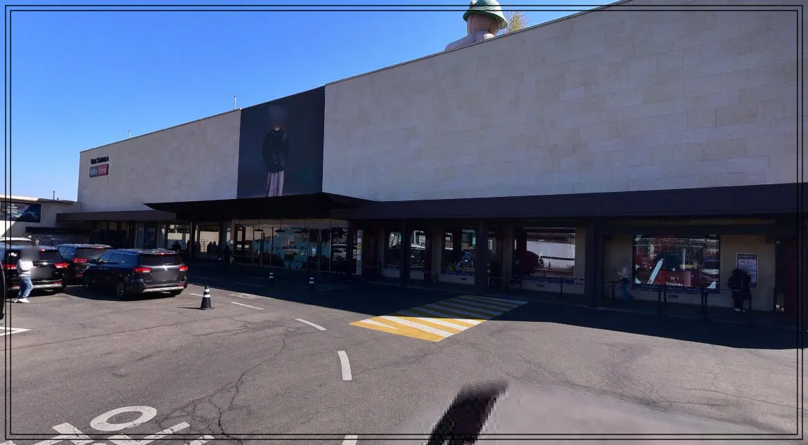 신라면세점-서울점-외부-전경-사진. 입구-앞에-차량들이-발렛주차를-기다리고-있으며,-건물에는-대형-광고-배너가-걸려-있음