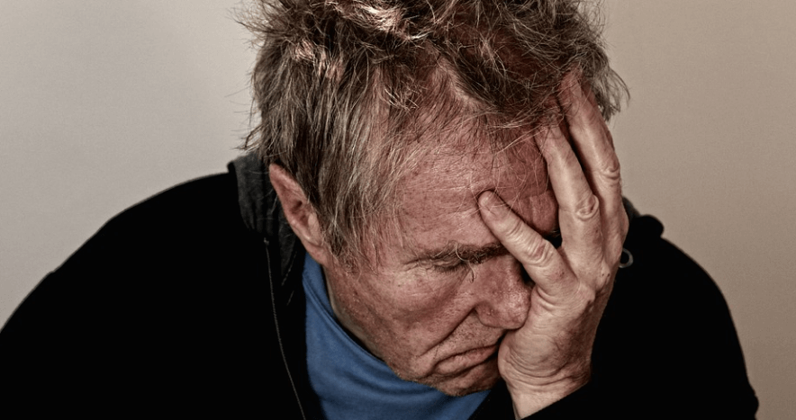 고통으로 손을 얼굴에 짚고 있는 노인