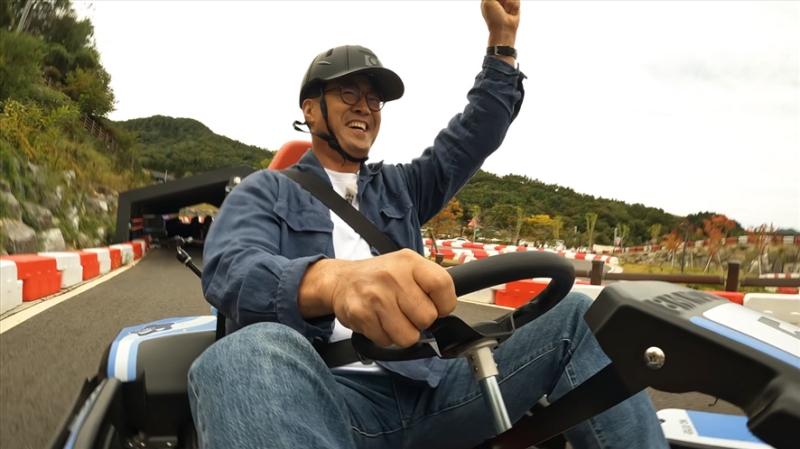 모자를 쓴 이만기가 카트를 운전하며 손을 든 모습