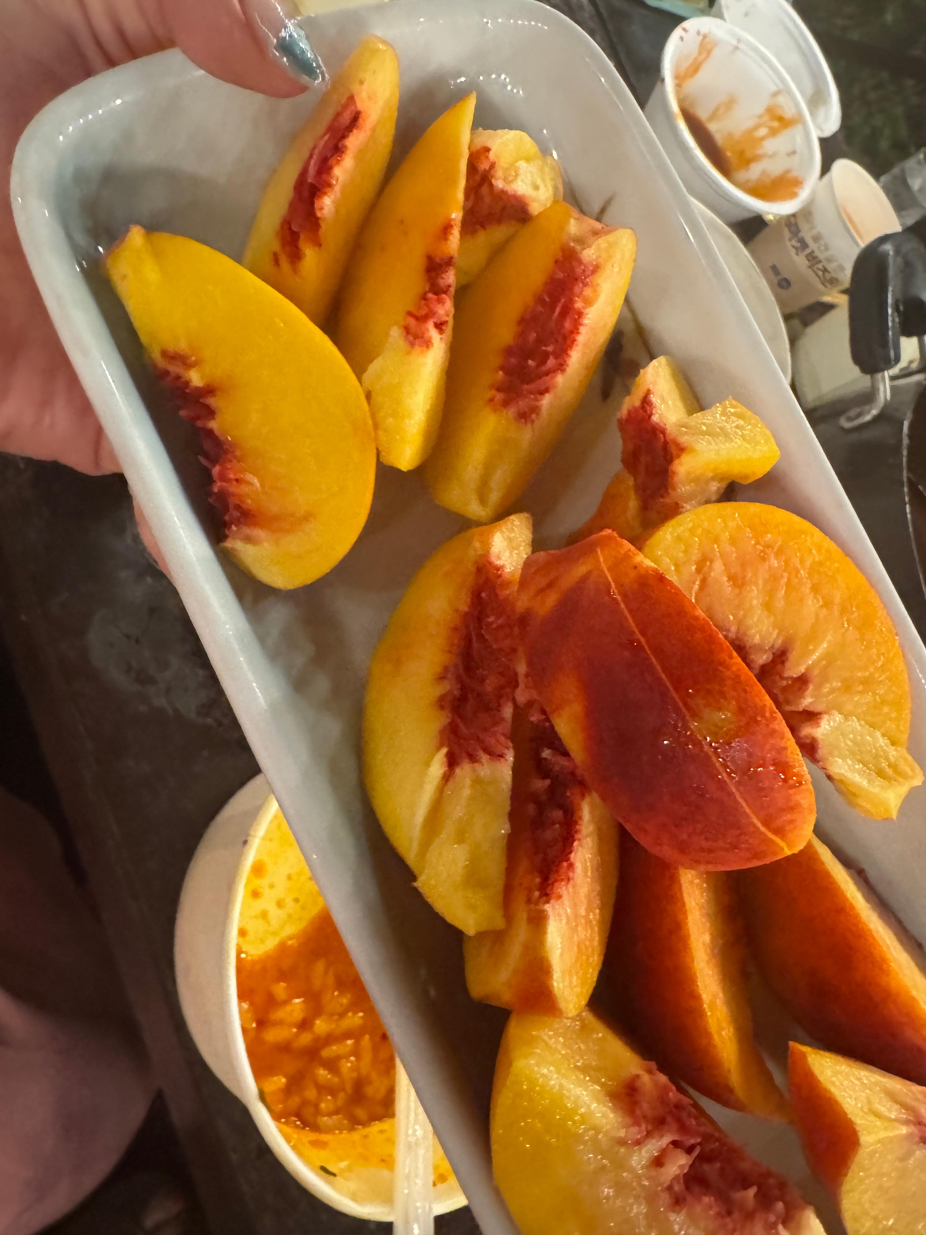 잘 익은 여름 복숭아를 접시에 담아낸 모습. 노릇한 살과 붉은 심지가 대비되어 보기만 해도 달콤하고 상큼하다.