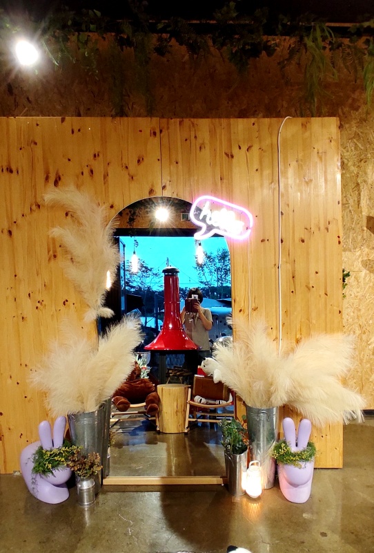 네온사인과 갈대 타원형 거울로 장식된 포토존