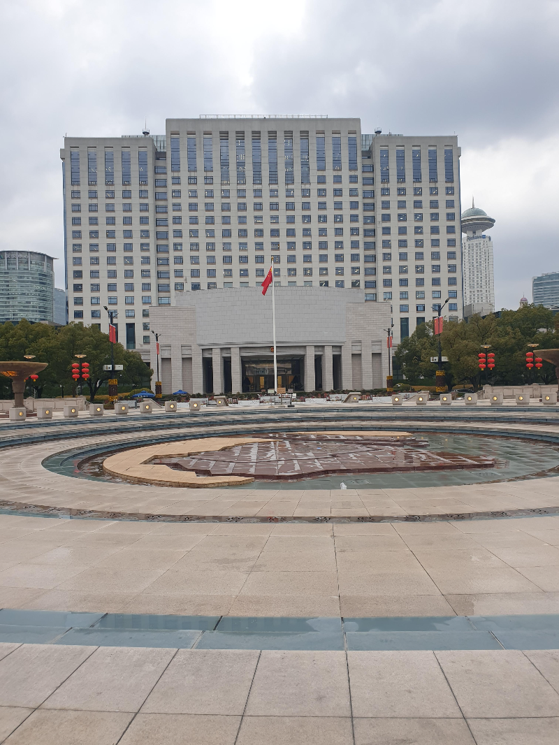땅이 젖어 있는 상하이 뮤직 분수. 그 뒤 중국 국기가 걸려 있다. 그 뒷 건물이 시청 청사.