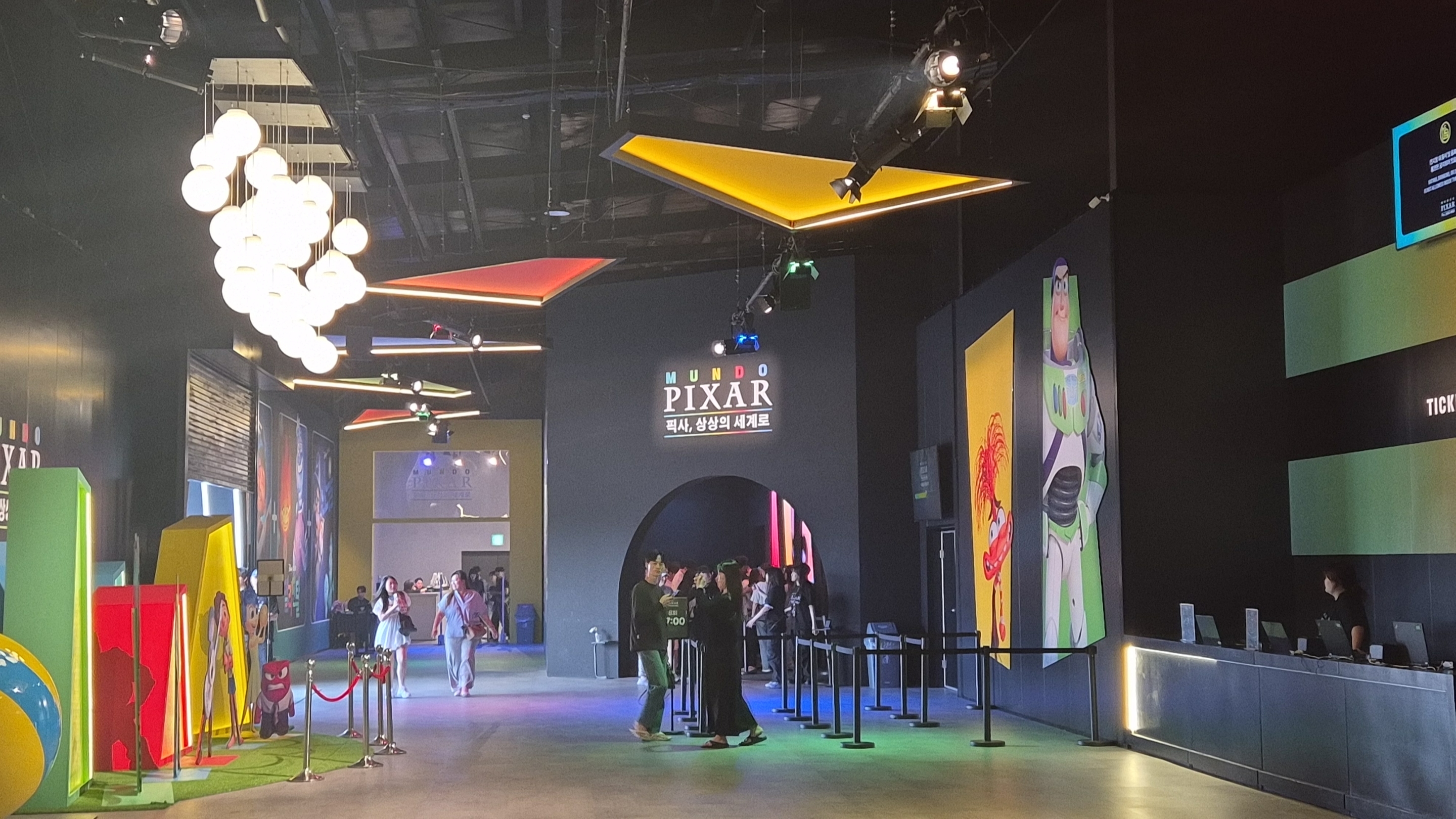 문도 픽사 서울 전시회 내부. 입구를 지나면 캐릭터 조형물과 포토존이 이어지고, 오른쪽에는 티켓 확인 데스크가 위치해 있다.