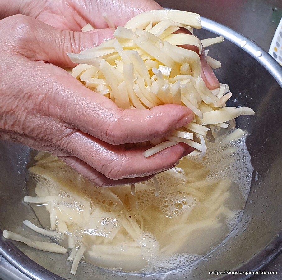 감자채볶음에 들어갈 절인 감자의 물기를 손으로 지긋이 짜서 제거하는 사진