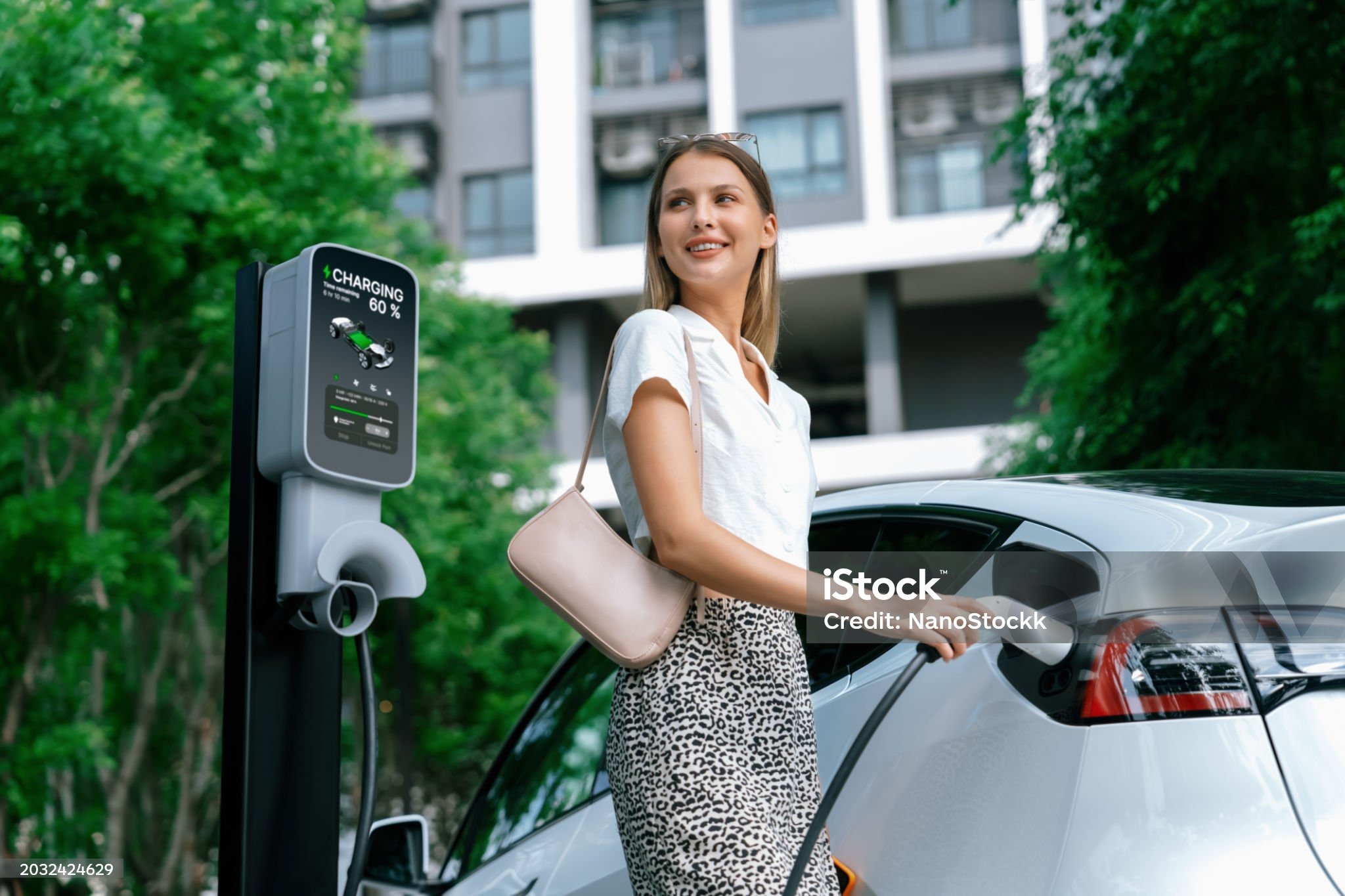 전기차를 충전하고 있는 여성. 유럽.