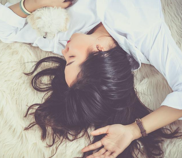 한손에는 하얀 강아지를 안고 한팔을 들고 잡을 자고 있는 하얀셔츠를 입은 여성