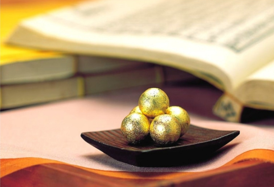 우황청심환 5개를 담은 네모난 나무 그릇을 바닥에 두고 주변에 옛 고서를 여러 권 놓아두고 찍은 사진