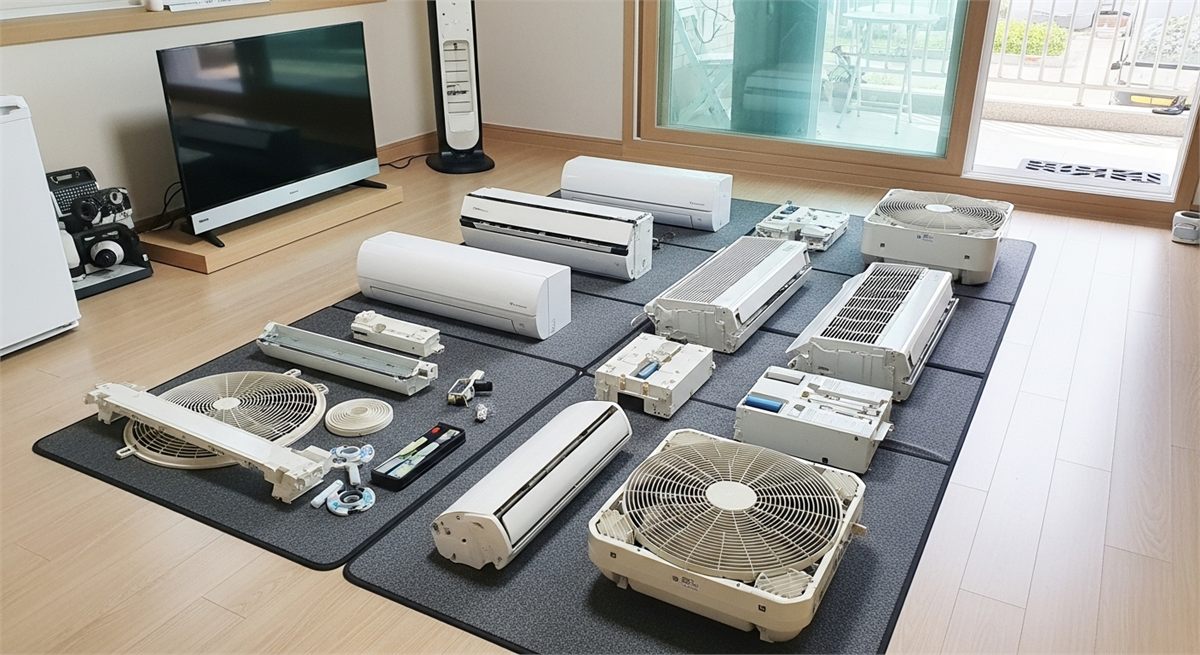  분해한 에어컨 부품을 보호매트 위에 정리해 둔 장면 