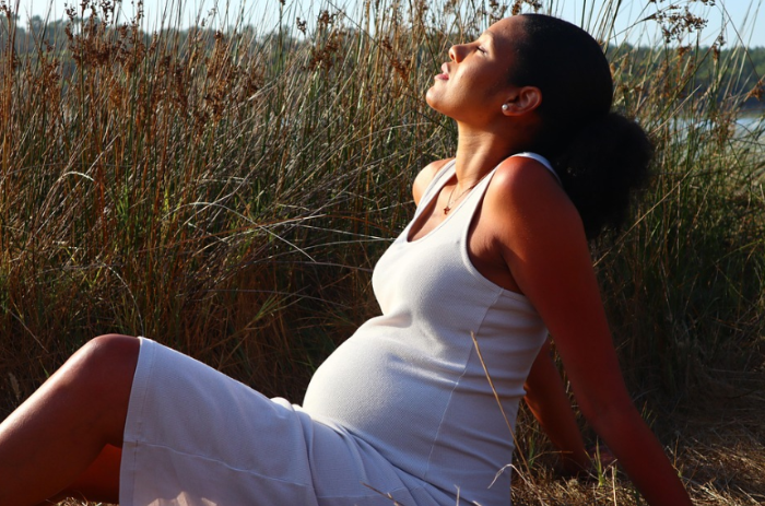 자연 속에서 햇살을 느끼며 여유를 즐기는 임신 중기의 여성 – 균형 잡힌 생활 습관이 만드는 평온한 순간