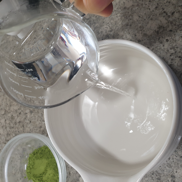 다완에 에스프레소 계량컵에 있는 물을 붓는 모습