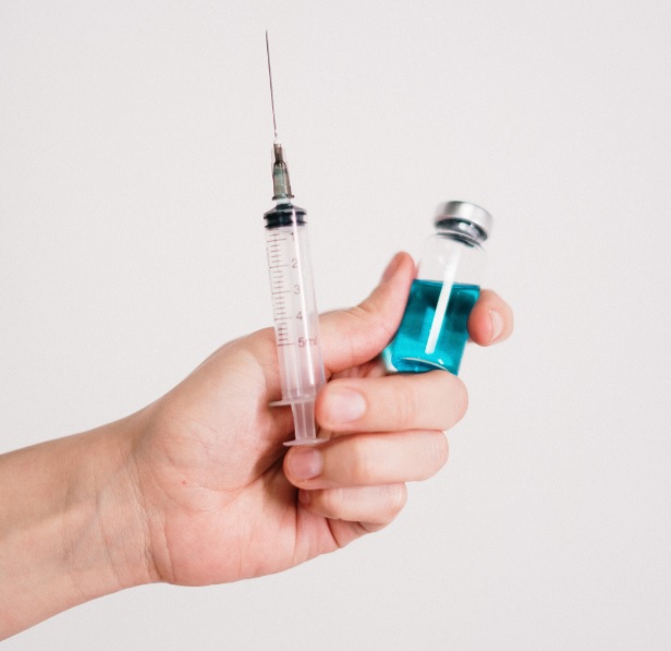 왼손으로 주사바늘과 주사약병을 들고있는 사진