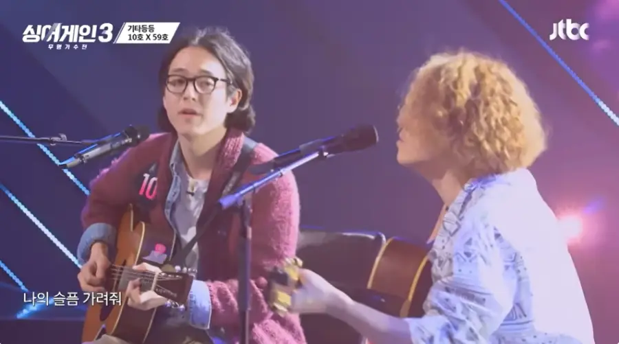 싱어게인3-
보라색무대배경 빨간스웨터에 검은 단발머리 검은뿔테안경을 쓰고 노래하는 10호와 흰셔츠 노란 곱슬머리로 노래하는 59호