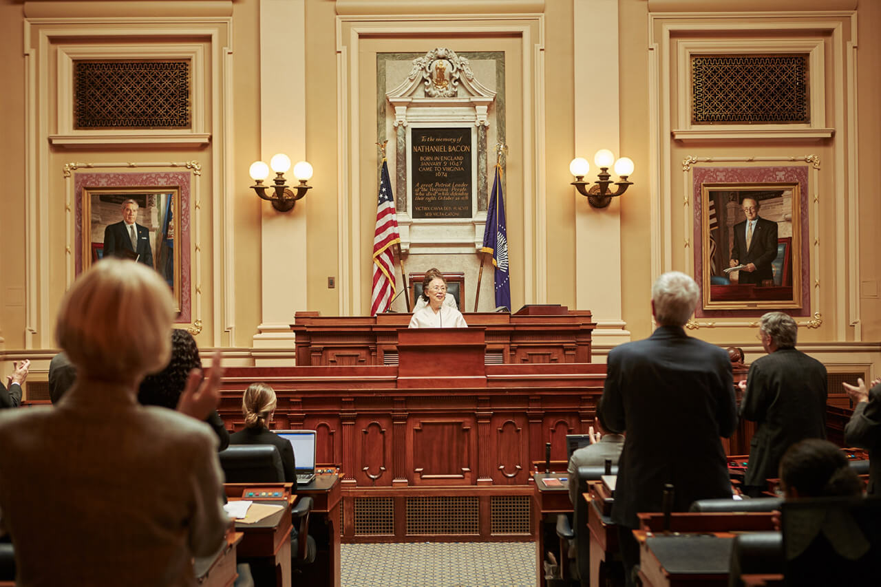 청문회장에서 연설하는 옥분과 그런 옥분에게 박수를 보내는 사람들