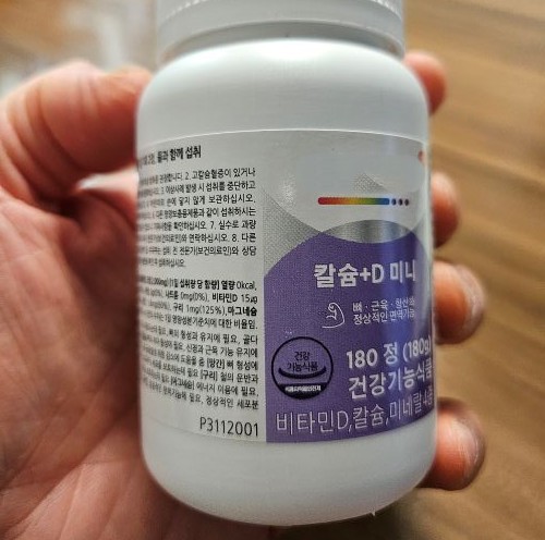 쉐어하우스 사장이 손에 들고 있는 건강기능식품 영양제 통의 성분표와 인증 마크