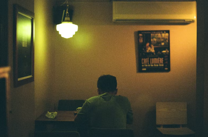 따뜻한 조명 아래에서 혼자 식사하는 남성의 모습. 감정 정리에 몰입한 조용한 식사 시간.