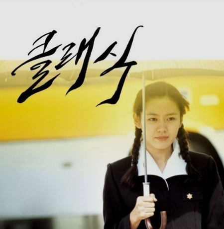 우산을 쓰고 버스 정거장을 지나가는 옛 교복을 입은 손예진 모습